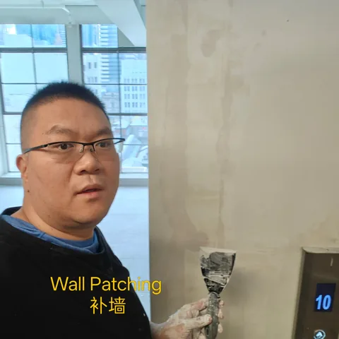 Handyman smoothing filler over a patched section of plaster wall