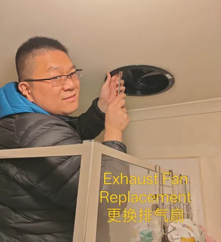 Handyman fixing a replacement ceiling exhaust fan into place