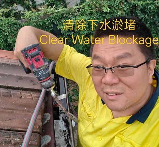 Handyman clearing a blocked gutter with a drill-driven cleaning hose